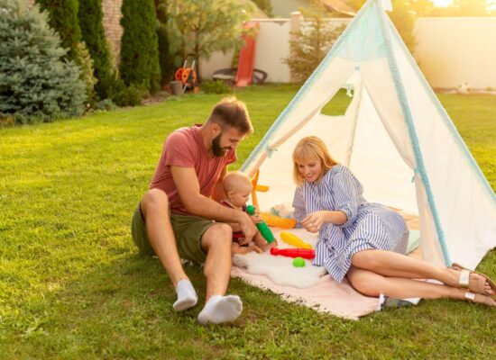 Family enjoying healthy green lawn in backyard with tent, representing safe outdoor space and professional lawn care