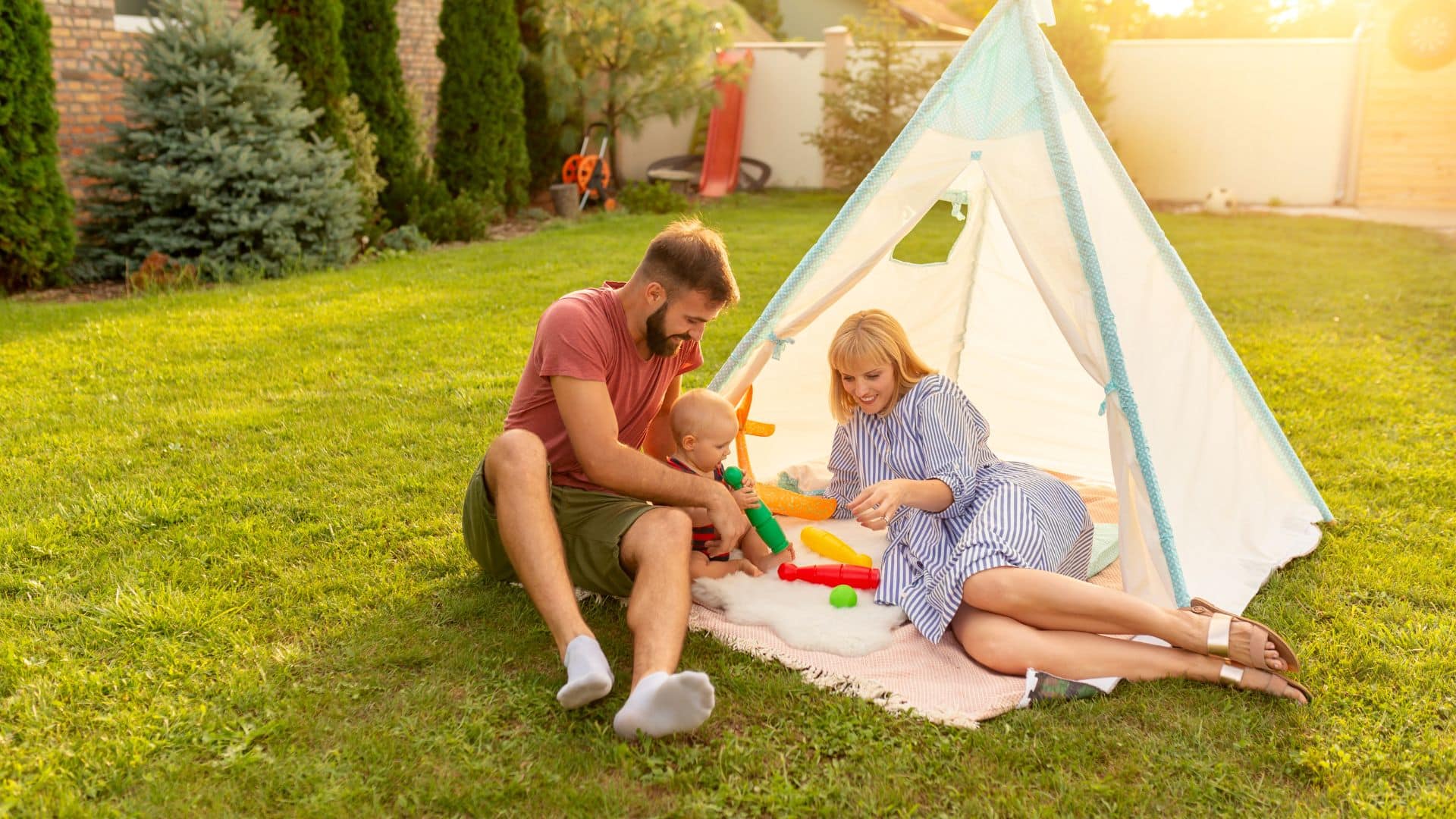 Family enjoying healthy green lawn in backyard with tent, representing safe outdoor space and professional lawn care