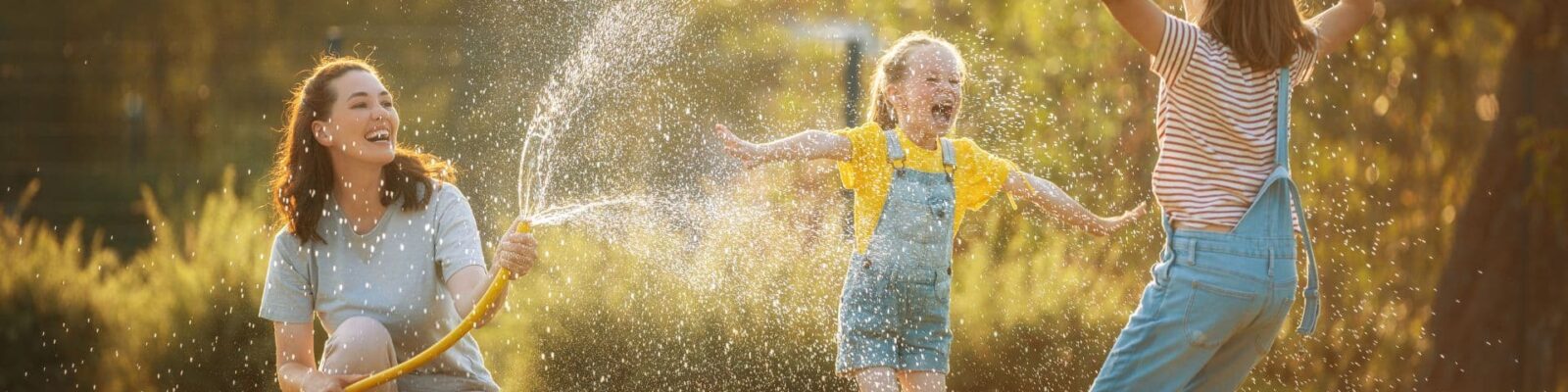 Family enjoying healthy backyard with children playing in water spray on lush green lawn