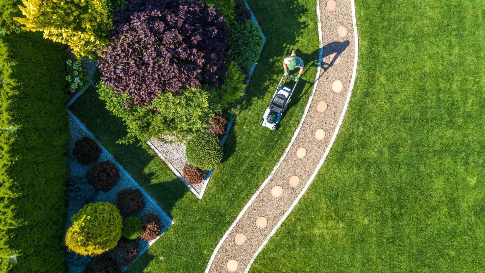 Aerial view of professional lawn care service treating residential yard with weed-free lawn and landscaped garden beds